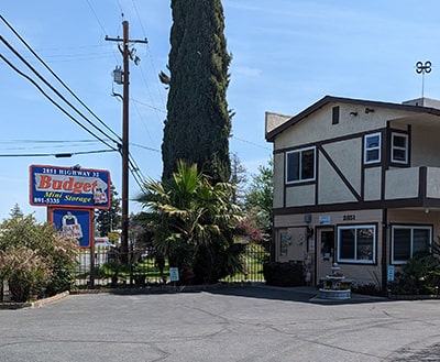 The exterior of Budget Mini Storage's office. It is a large beige building.